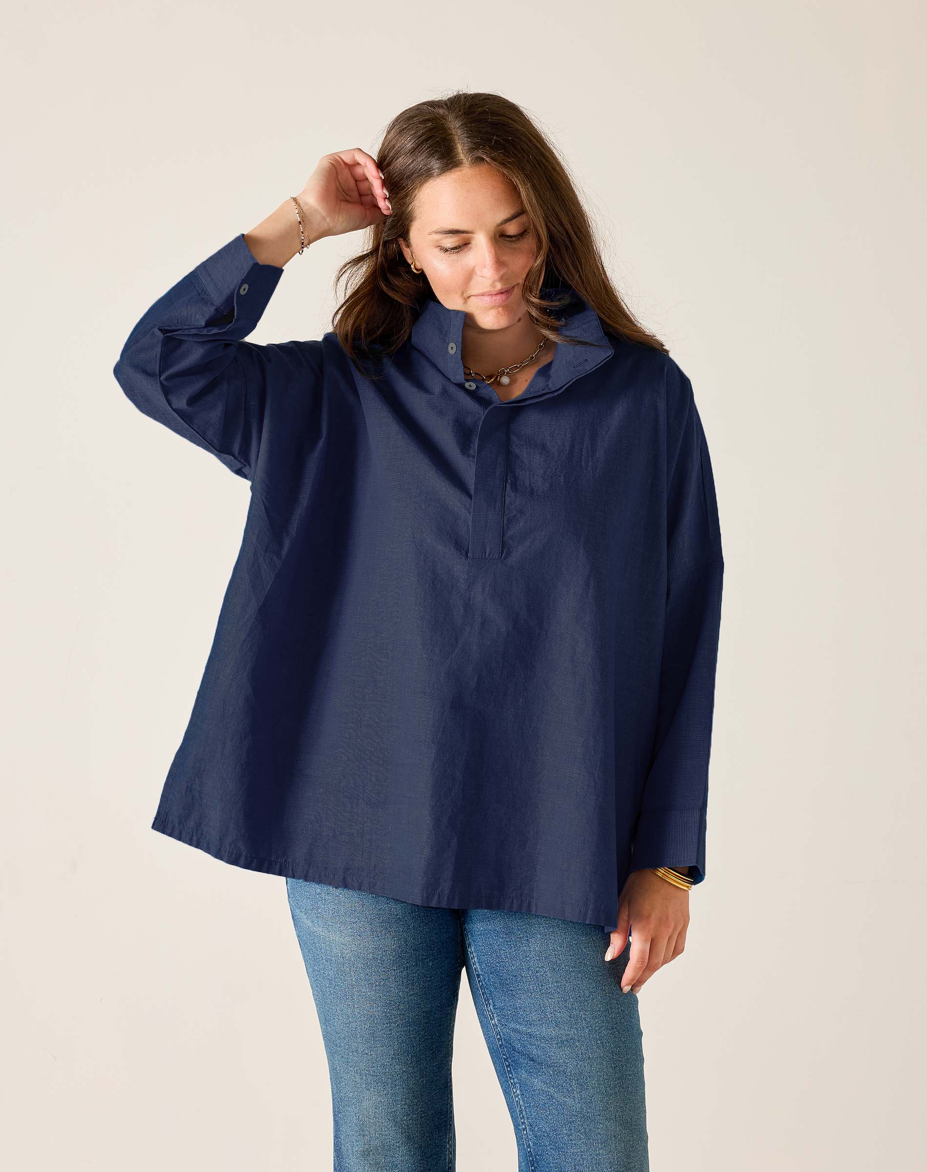 Woman wearing a navy raincoat against a plain background
