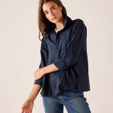 Woman wearing a navy shirt and blue jeans against a plain background