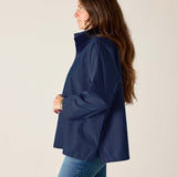 Woman wearing a navy blue jacket and jeans on a plain background
