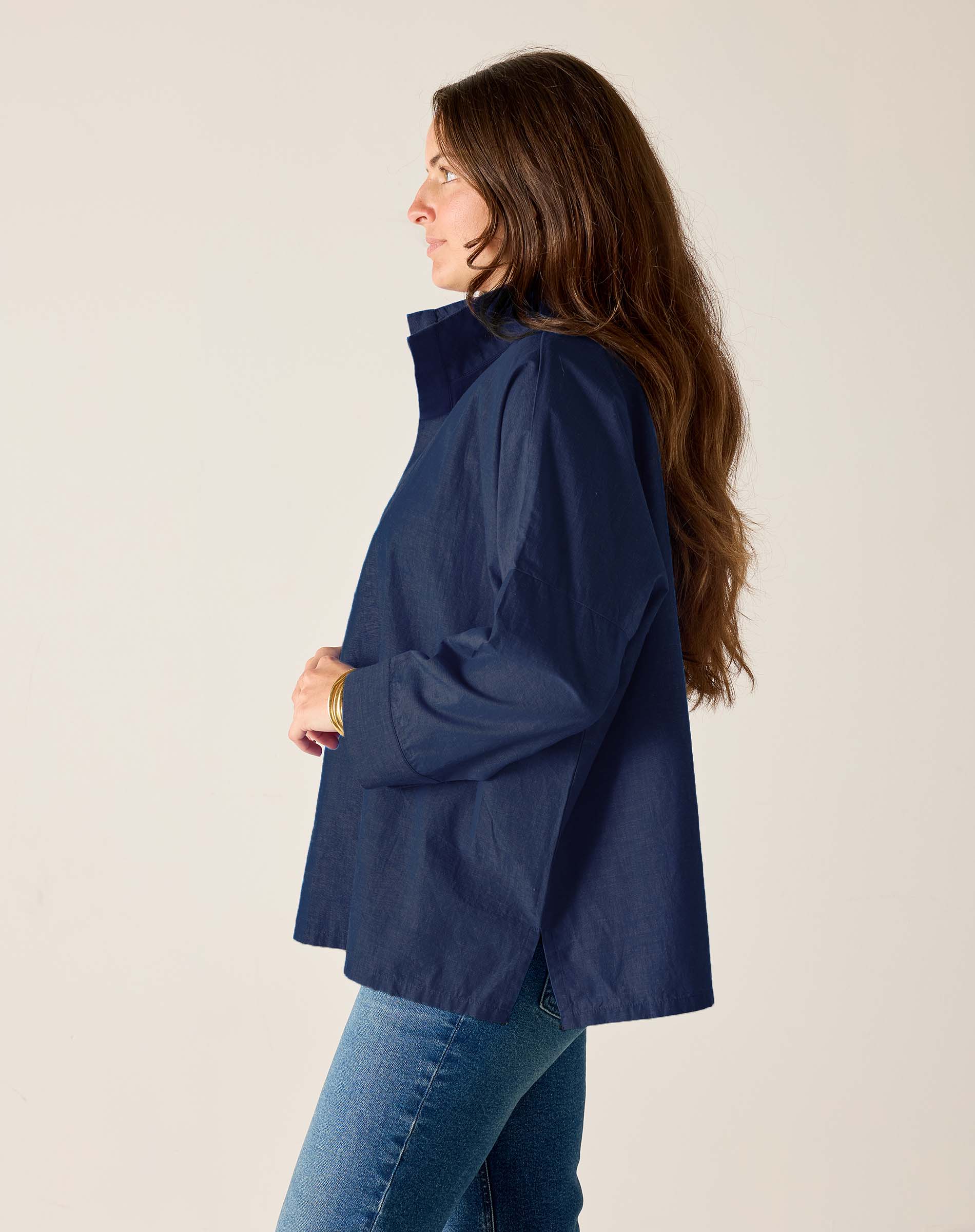 Woman wearing a navy blue jacket and jeans on a plain background