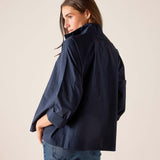 Person wearing a navy jacket and blue jeans against a plain background