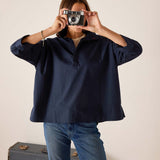 Person wearing a navy blue shirt and blue jeans holding a vintage camera.