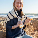 Woman sitting on a beach holding a striped towel