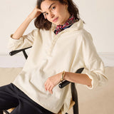 Opal beige oversized linen tunic top with a front henley-style buttoned placket and rolled sleeves.
