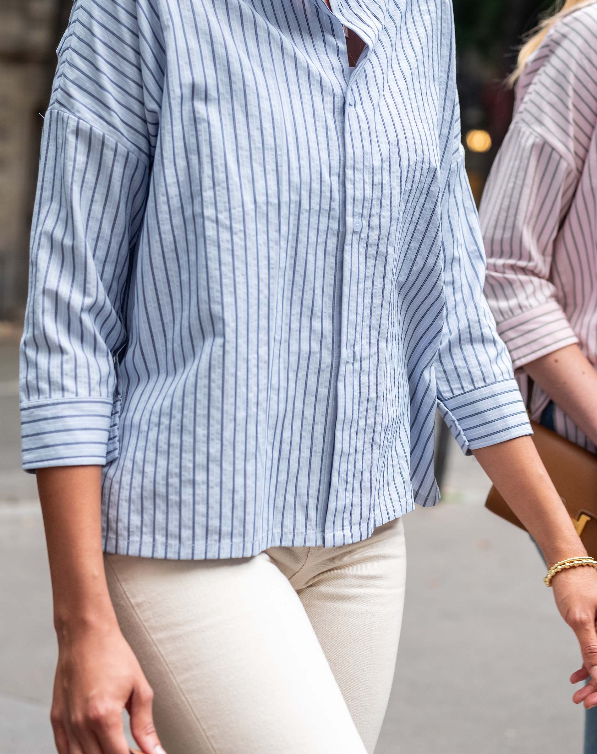 Person wearing a blue and white striped shirt with beige pants, standing outdoors.