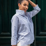 Woman wearing a blue and white striped shirt against a dark green door.