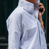 Person wearing a blue and white striped shirt with a blurred background