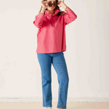 Woman wearing a pink jacket and blue jeans against a white background