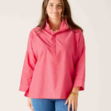 Woman wearing a pink long-sleeve shirt and blue jeans against a white background