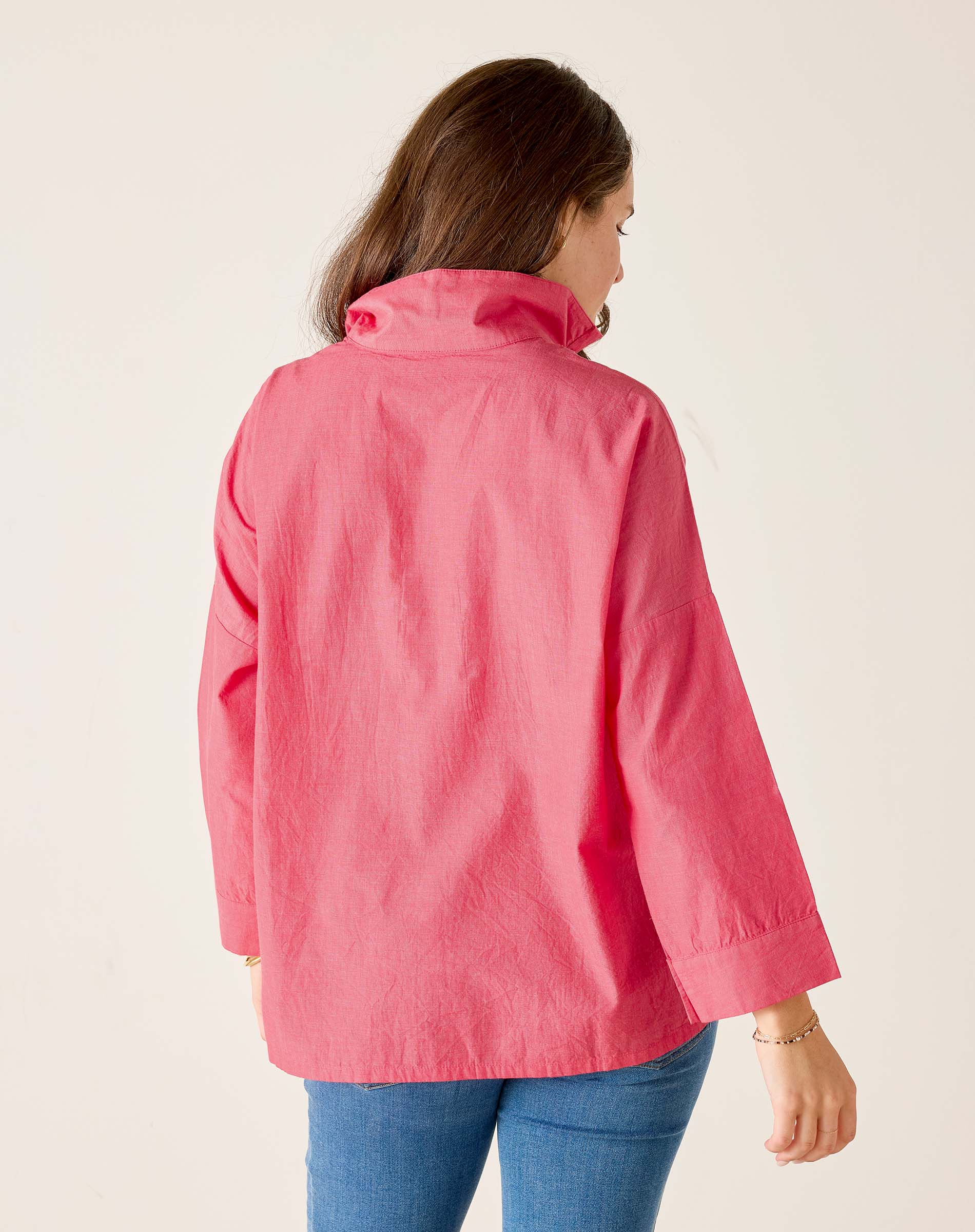 Person wearing a pink jacket on a plain background