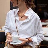 Woman in a white shirt holding a cup in a cafe setting