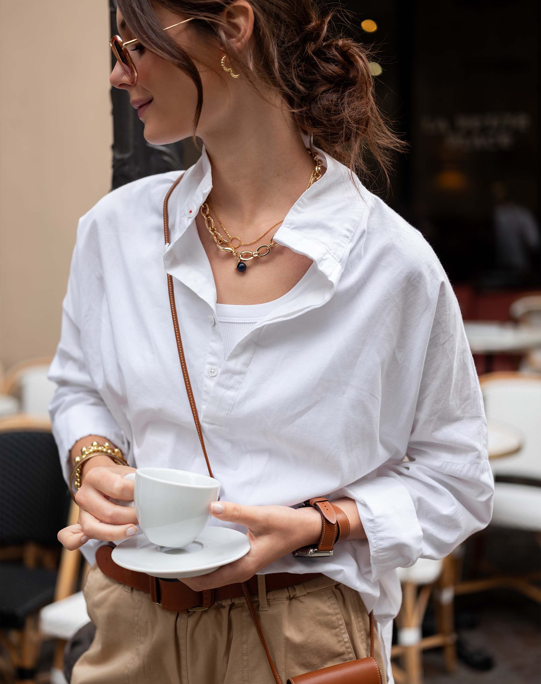 Woman in a white shirt holding a cup in a cafe setting