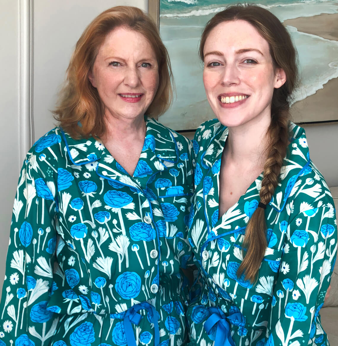 two females wearing matching pajama floral print set in front of a painting 