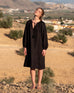 female wearing black linen long sleeve dress with tassel ties  standing on a rocky hill in spain