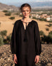female wearing black linen long sleeve dress with tassel ties up close on a rocky hill in spain