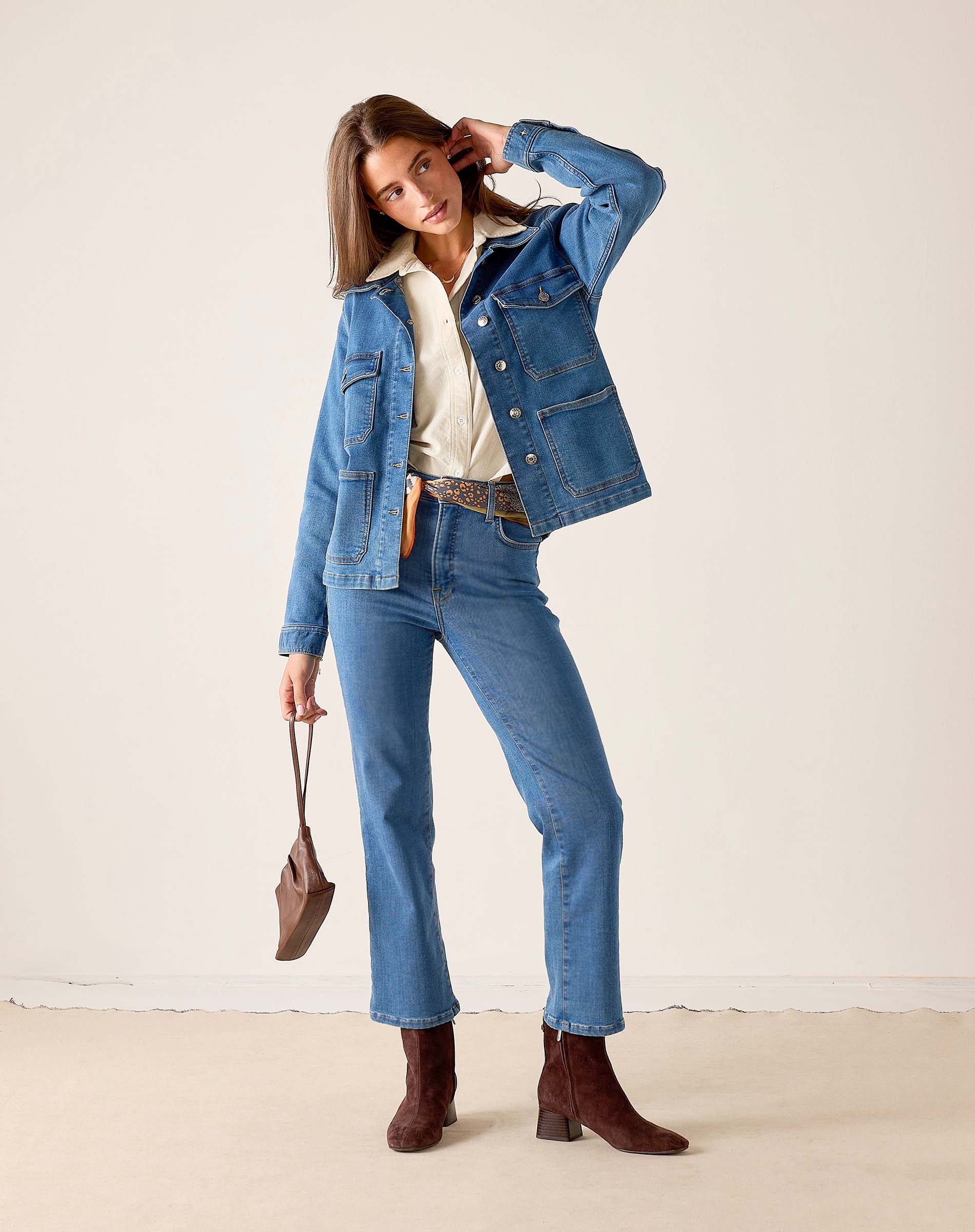 MERSEA ladies' travel-ready mid-wash denim field jacket over a cream top and matching jeans.