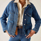 Medium blue denim field jacket with front pockets and a button closure.