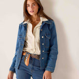 Blue denim field jacket with buttons over a cream button-down shirt and jeans.