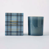 MERSEA women's travel-friendly fireside flannel plaid box candle in a textured blue and navy checkered container with the product name printed on it.