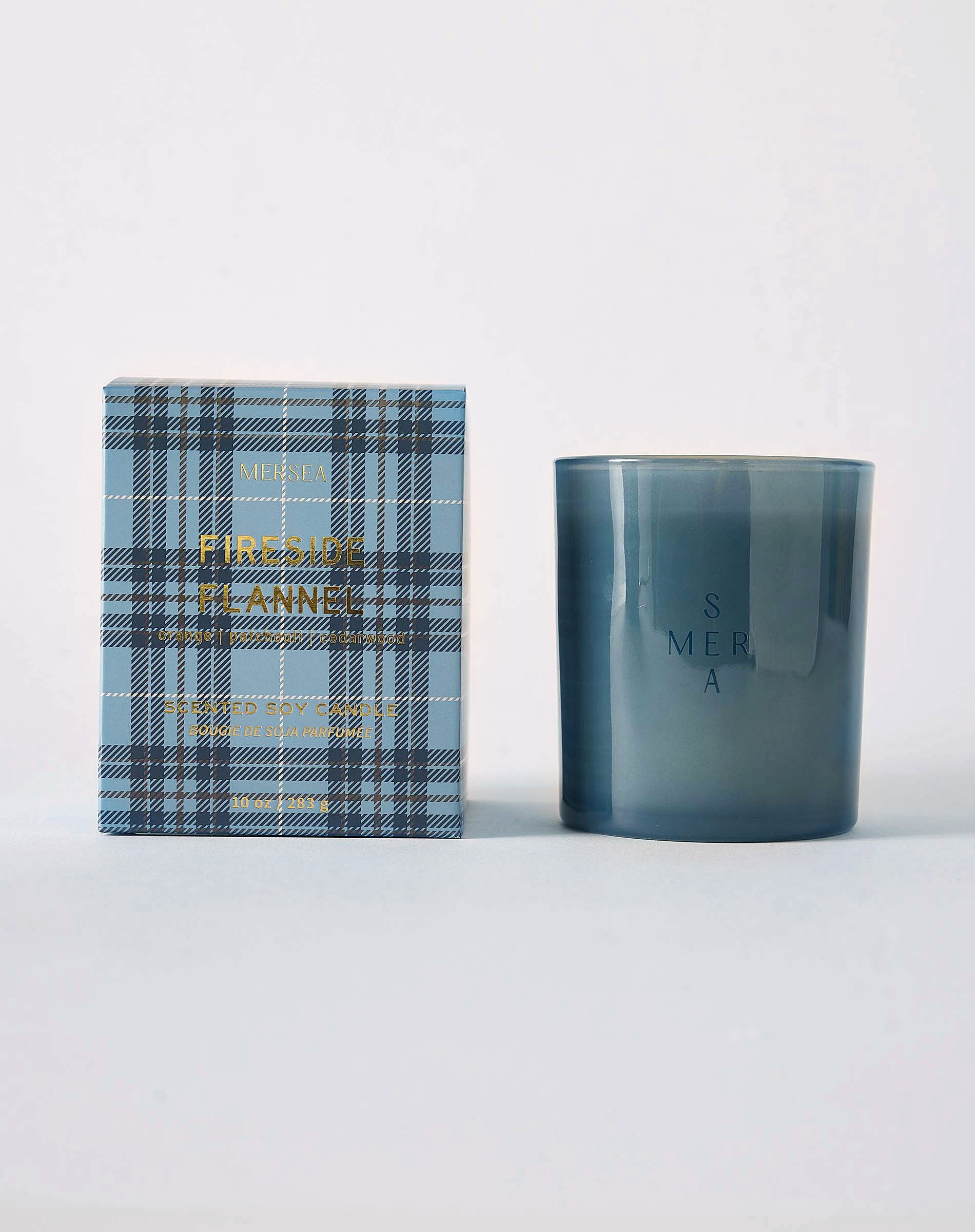 MERSEA women's travel-friendly fireside flannel plaid box candle in a textured blue and navy checkered container with the product name printed on it.