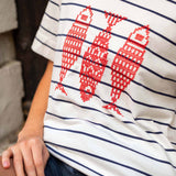 Close-up of a person wearing a striped shirt with red fish designs.
