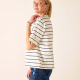 Woman wearing a striped shirt and jeans against a plain background
