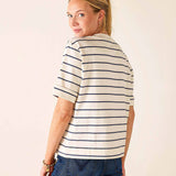 Woman wearing a striped shirt and jeans against a plain background