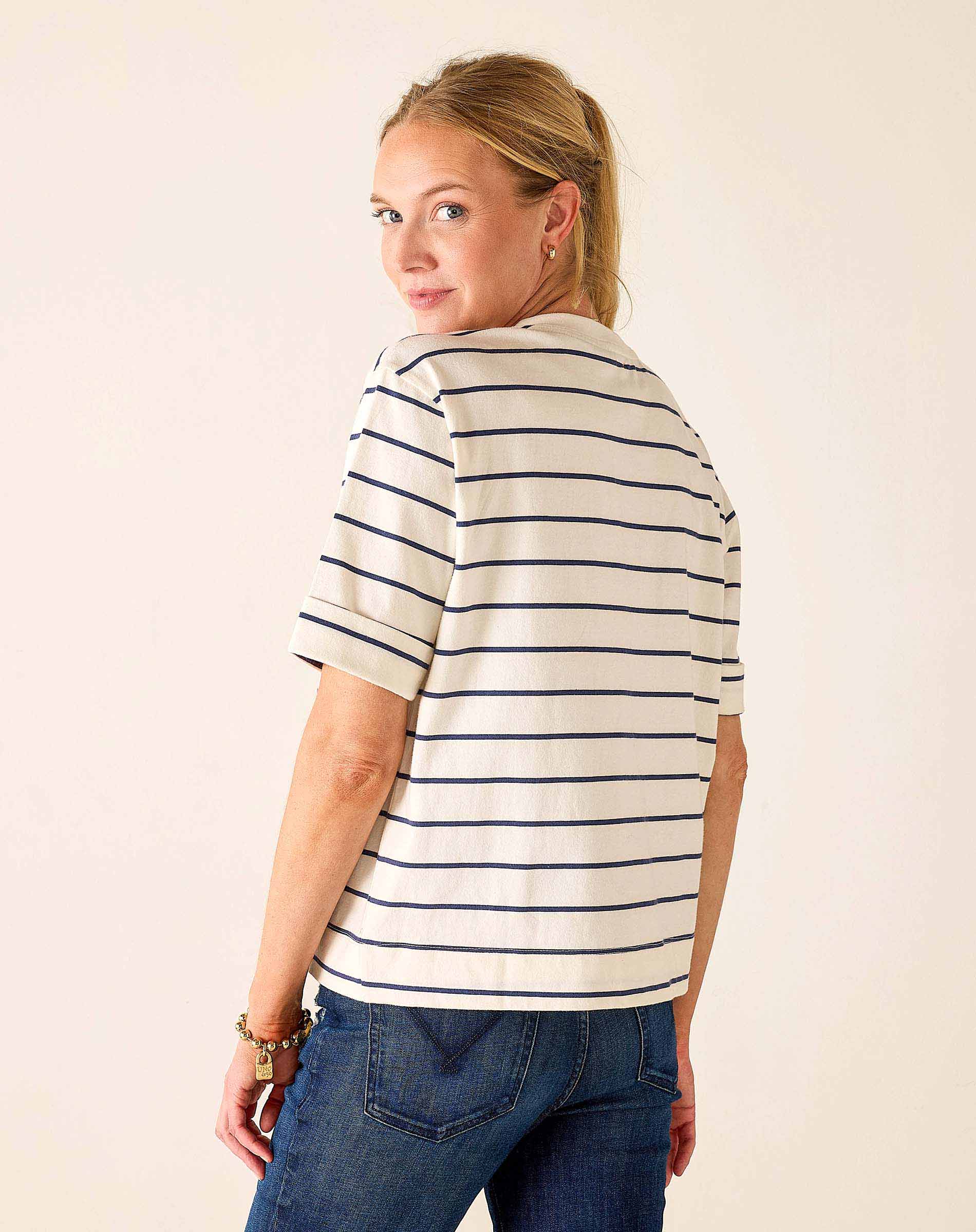 Woman wearing a striped shirt and jeans against a plain background