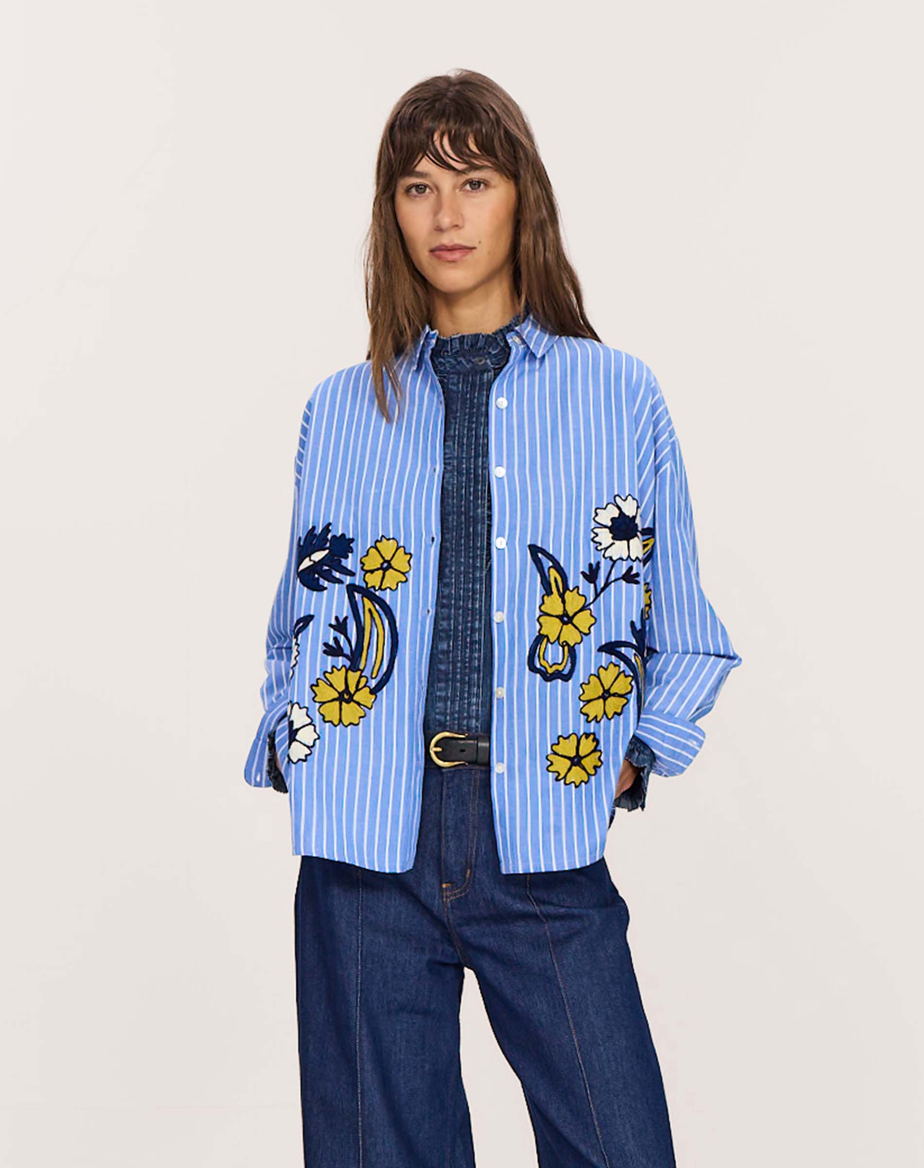 Women's travel-friendly light blue and white striped button-down shirt featuring large embroidered yellow and white floral details.