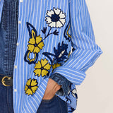 Blue and white striped cotton shirt with embroidered yellow and white floral details and button-down front.