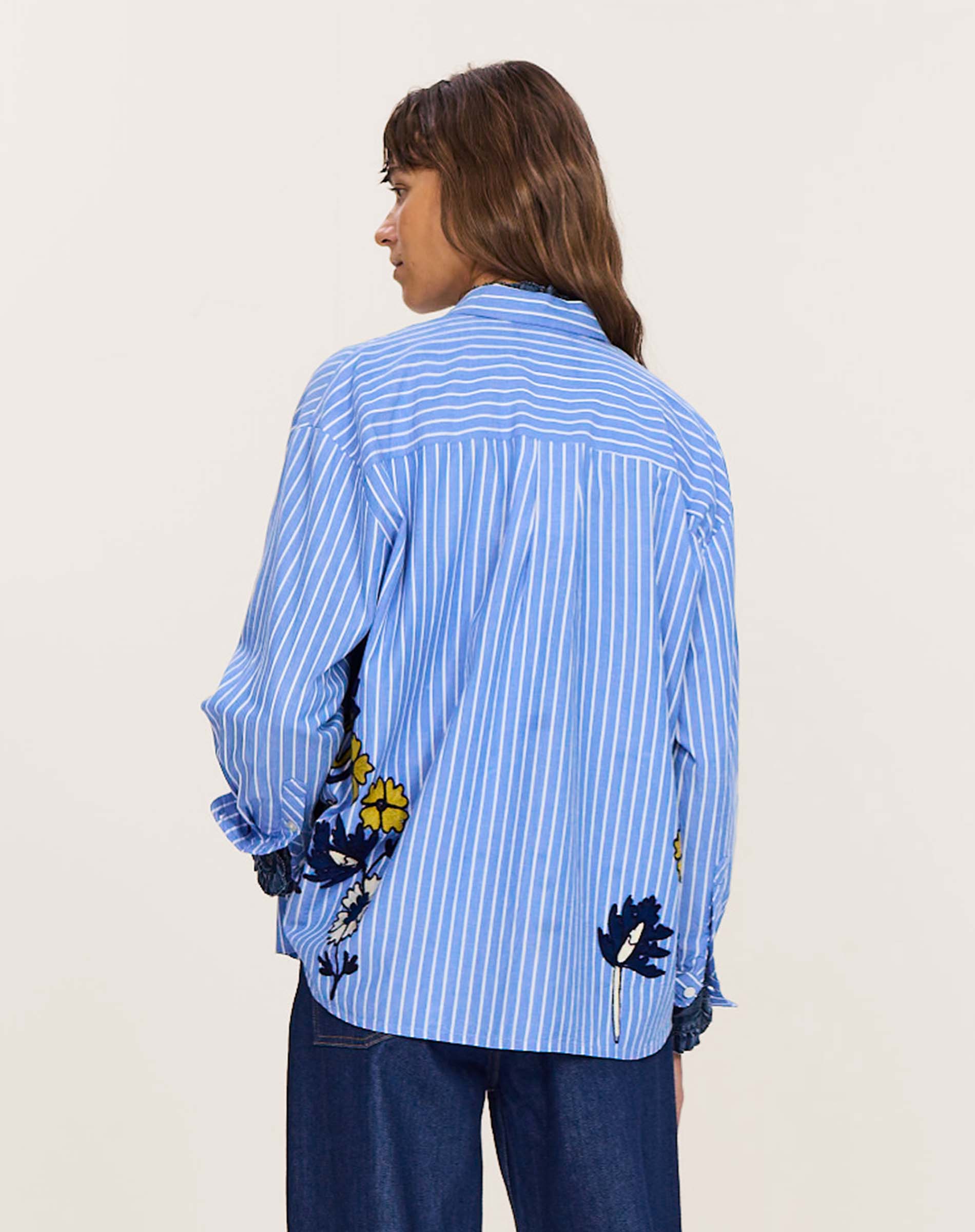 Side view of women's travel-friendly blue and white striped button-down shirt with floral embroidery details.