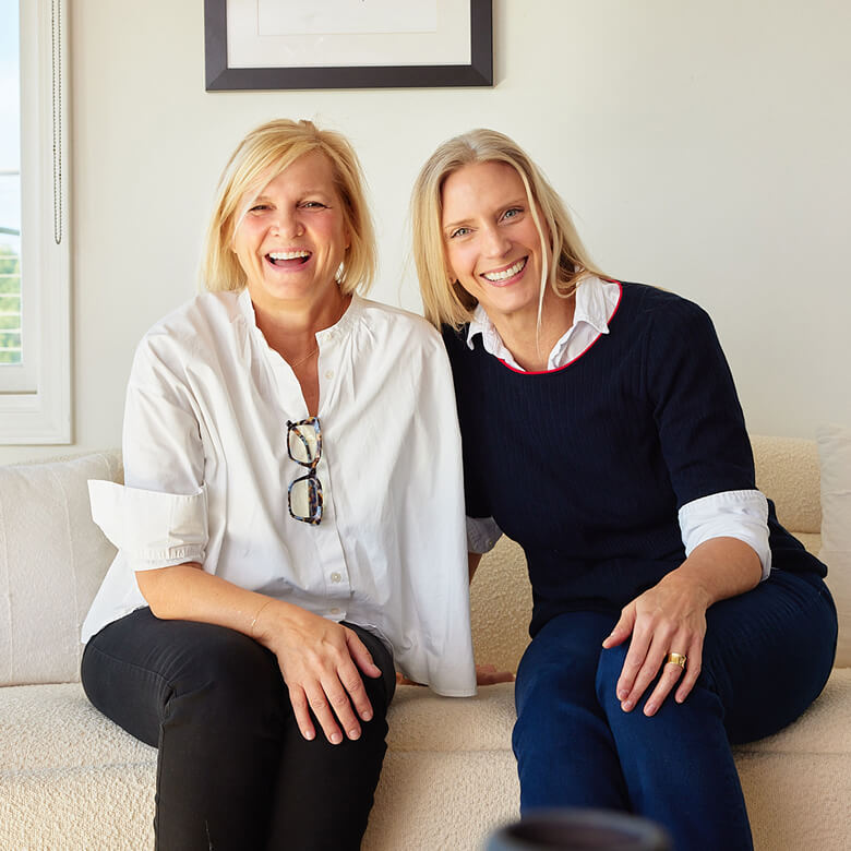 Two women sitting on a couch in a bright room