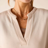 Bone knit top with a wide V-neckline and ribbed trim
