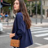 Woman in a blue coat with a brown handbag on a city street
