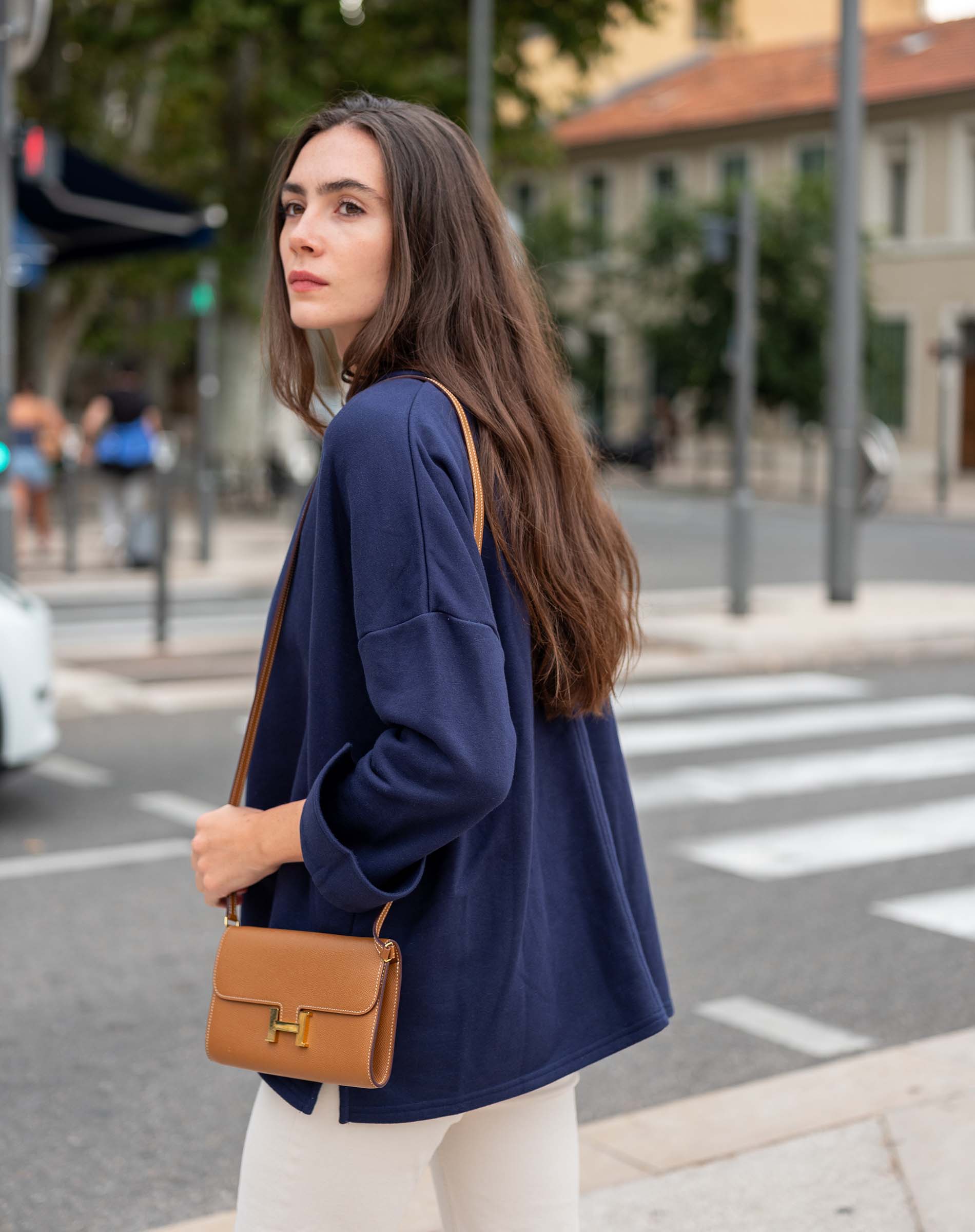 Woman in a blue coat with a brown handbag on a city street