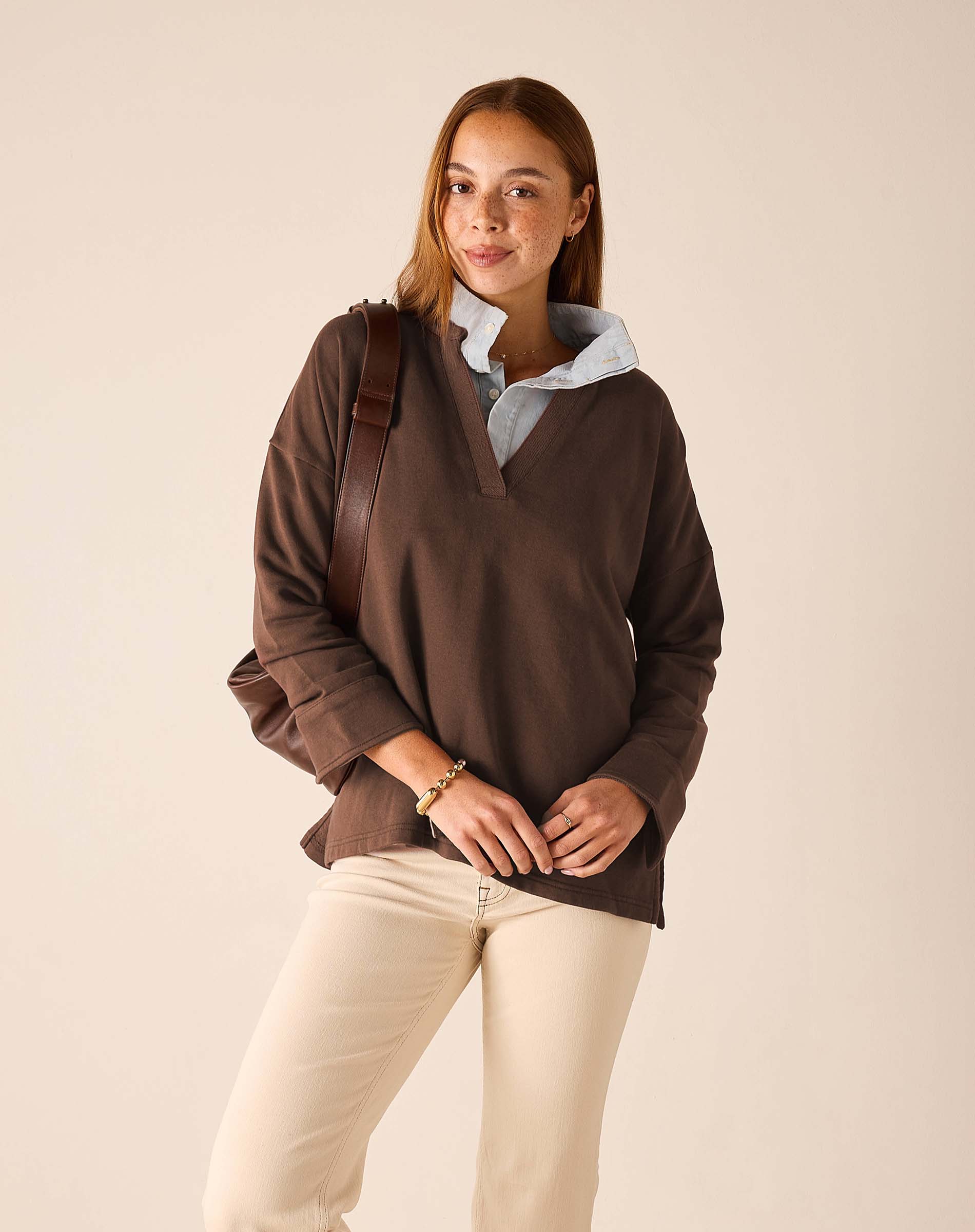 Espresso knit top with a wide neckline and a light blue button-down shirt layered underneath.