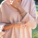 Person wearing a light pink outfit with a blurred green background