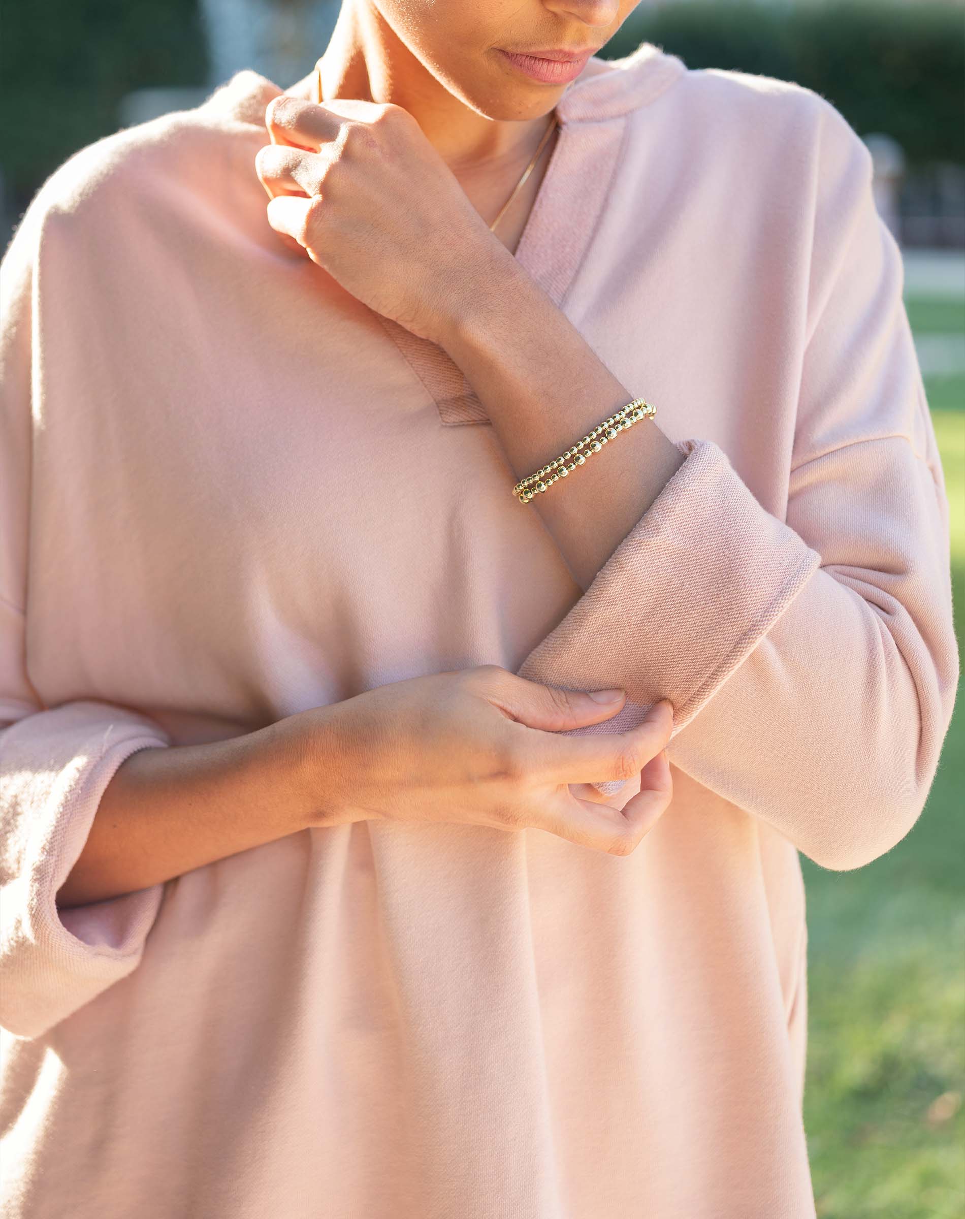 Person wearing a light pink outfit with a blurred green background