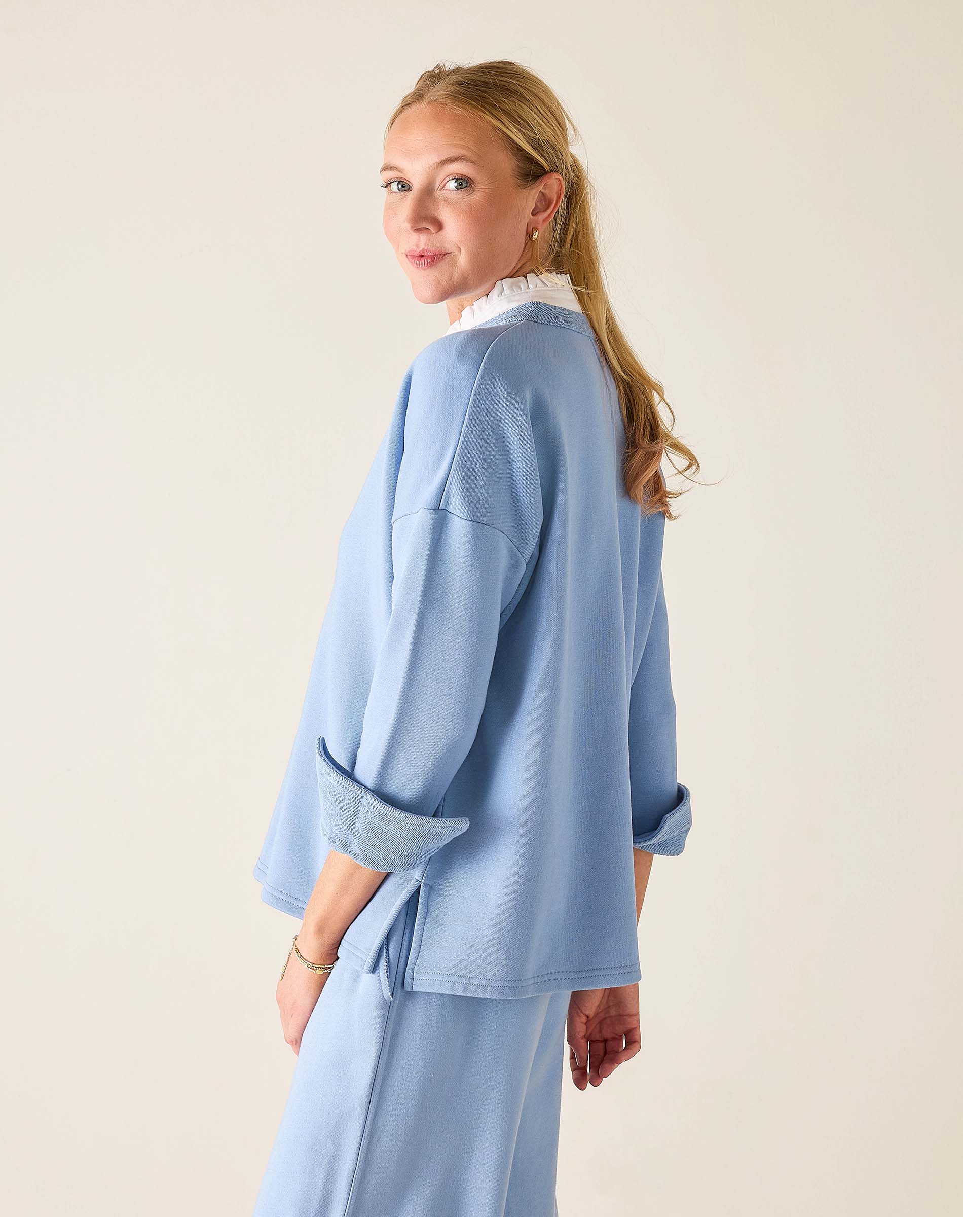 Woman wearing a light blue outfit against a plain background