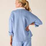 Woman wearing a light blue outfit against a beige background