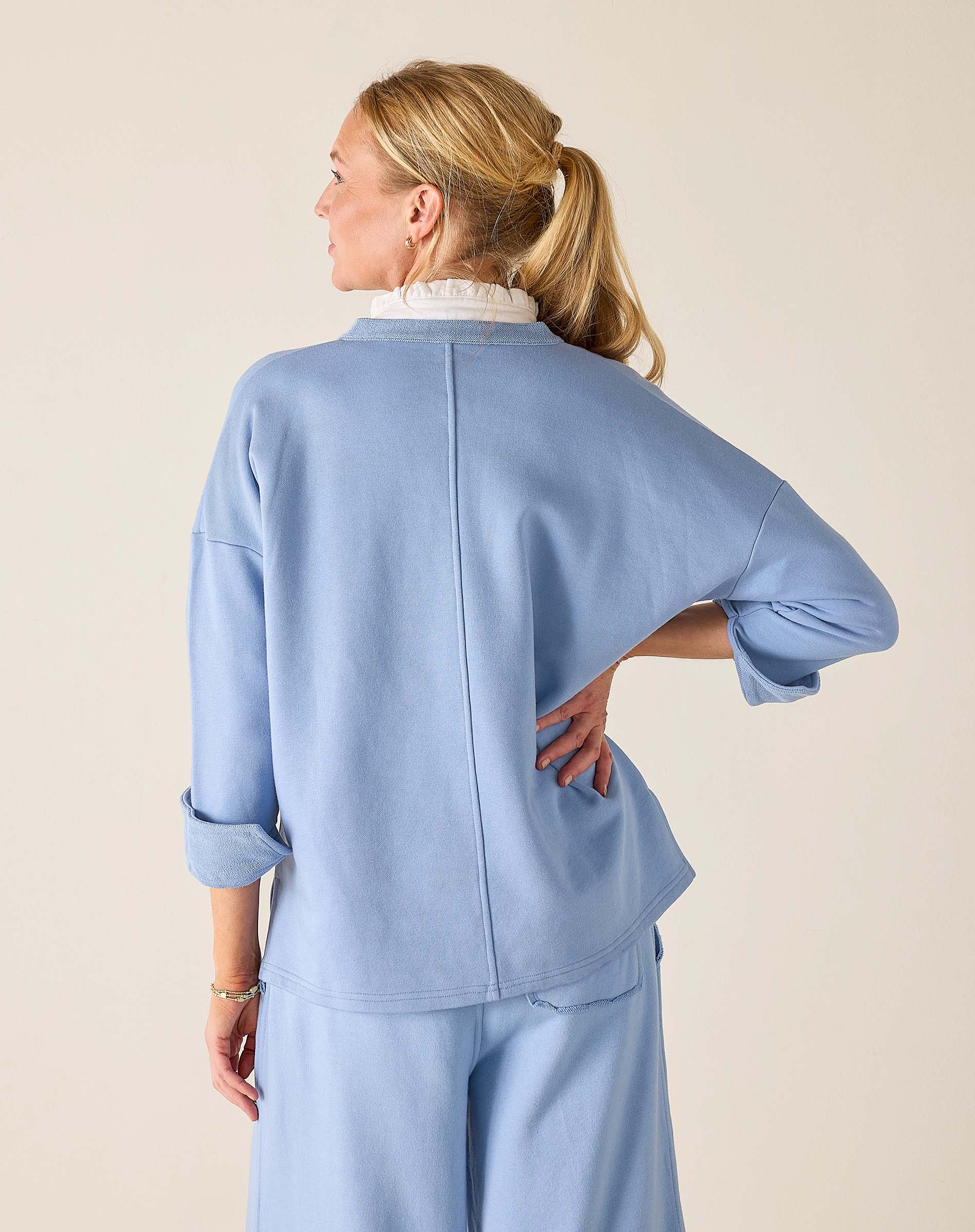 Woman wearing a light blue outfit against a beige background