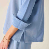 Light blue outfit with rolled-up sleeves on a neutral background