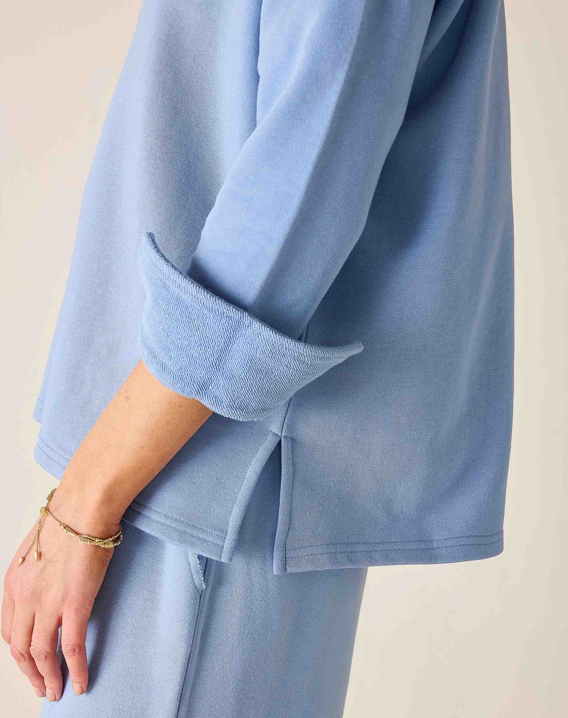 Light blue outfit with rolled-up sleeves on a neutral background