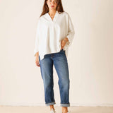 Woman wearing a white blouse and blue jeans against a plain background