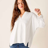 Woman wearing a white blouse and blue jeans against a plain background