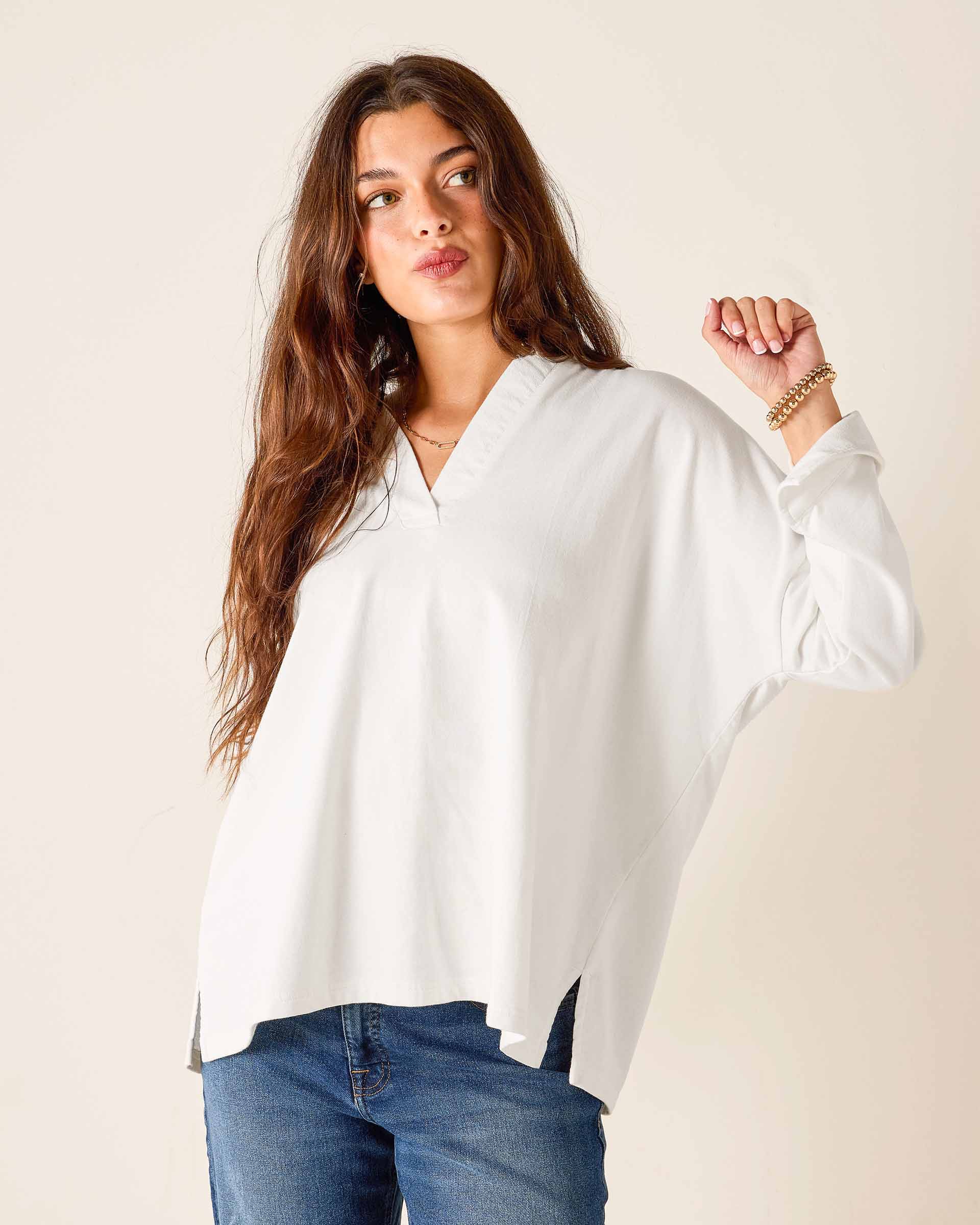 Woman wearing a white blouse and blue jeans against a plain background