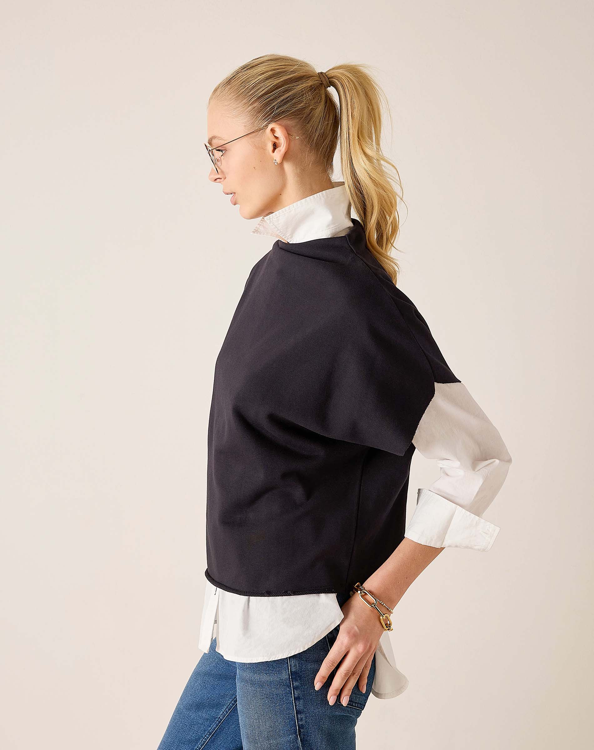 Side view of women's travel-friendly black dolman top over a white button-down shirt.