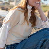 Bone-colored dolman sleeve knit top paired with blue jeans in a beach setting.