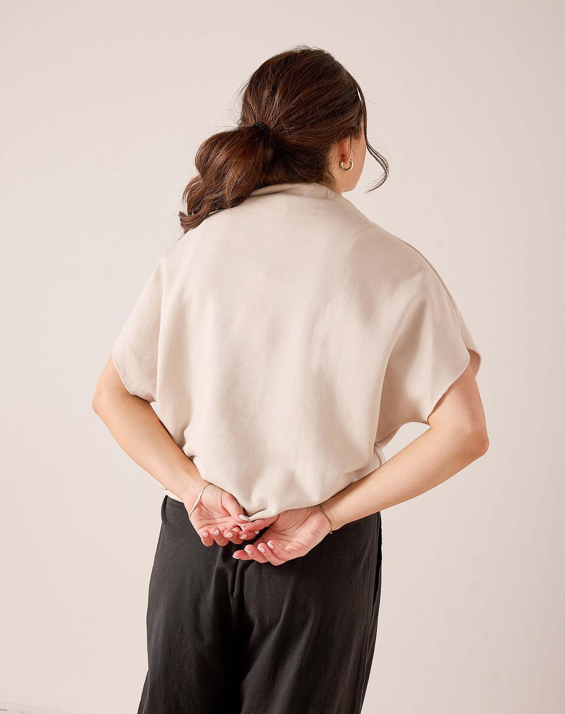 Back view of women's travel-friendly bone-colored dolman top with relaxed fit and soft knit construction.