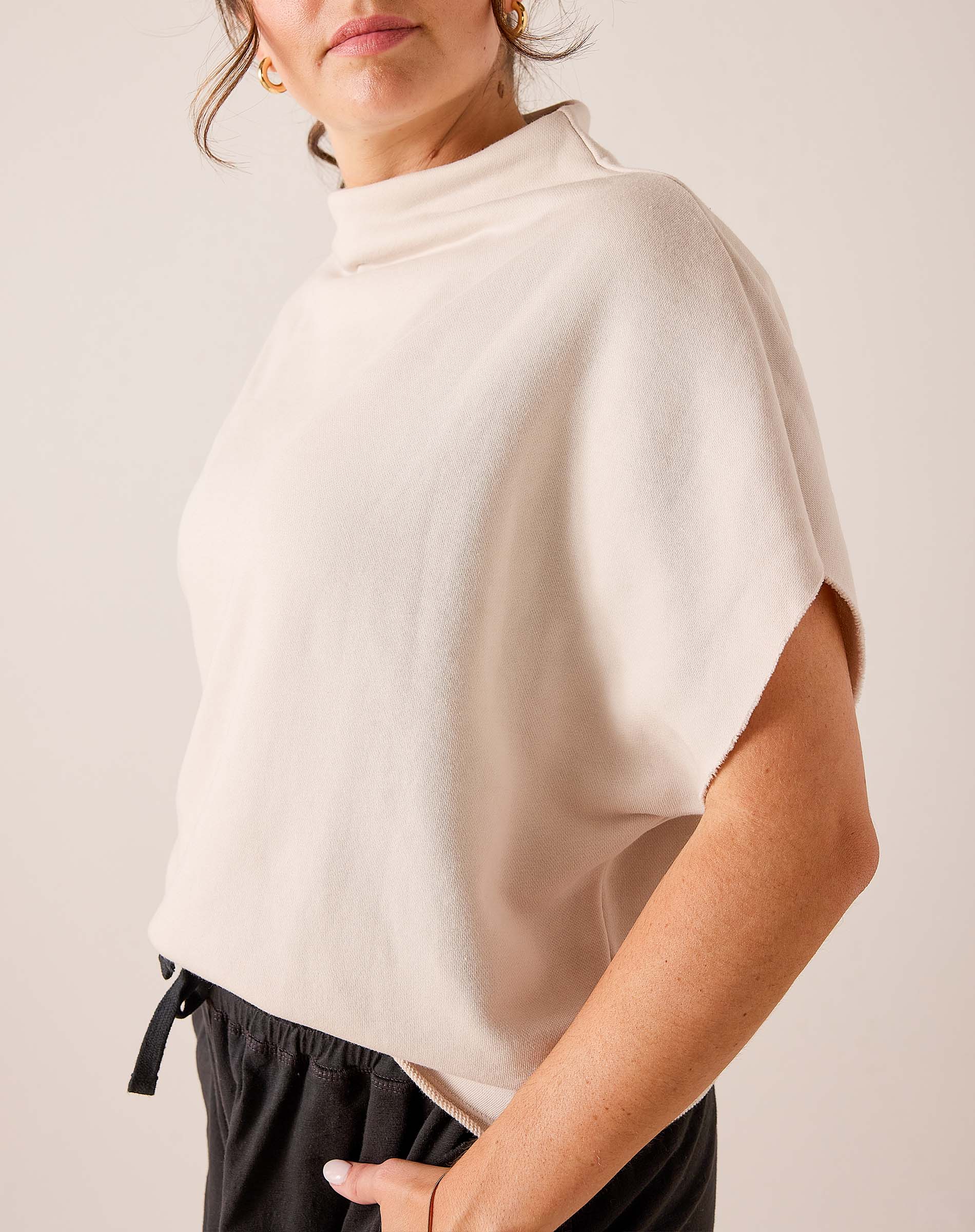 Bone colored dolman sleeve knit top with high neckline and relaxed fit.